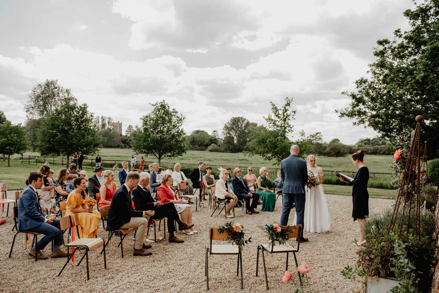 abbey hall eye suffolk wedding smiling bride walking down the aisle carrying a pink peony bouquet by anne schwarz photography