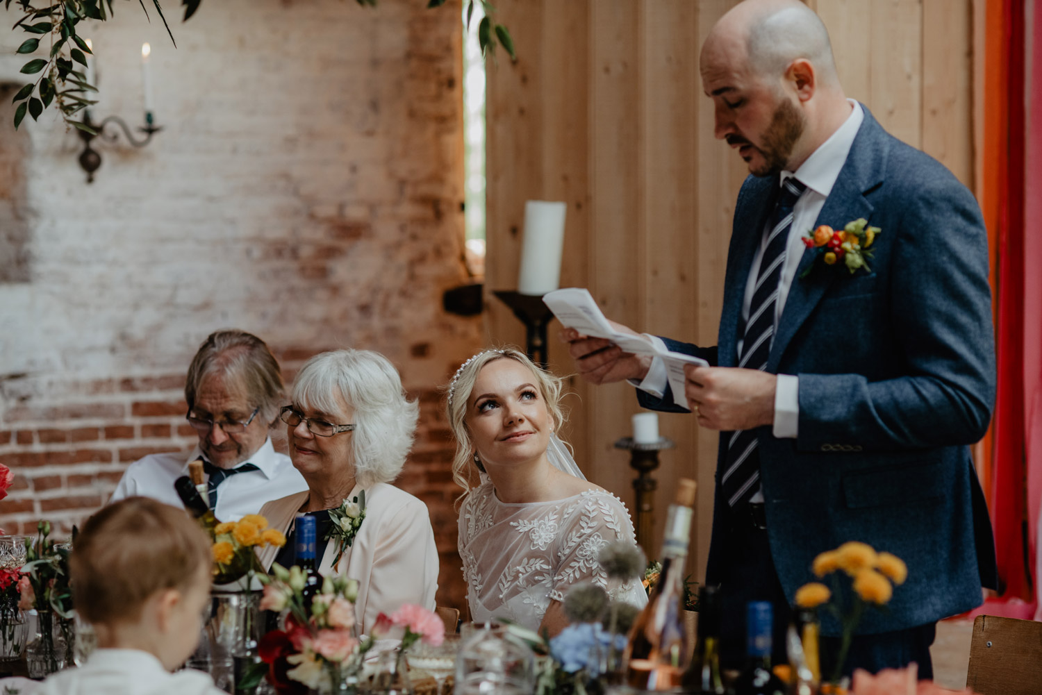 abbey hall eye suffolk wedding smiling bride walking down the aisle carrying a pink peony bouquet by anne schwarz photography