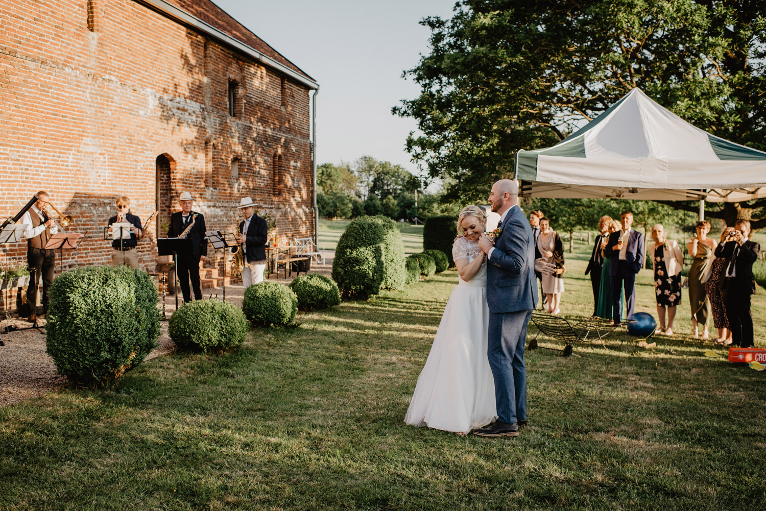 abbey hall eye suffolk wedding smiling bride walking down the aisle carrying a pink peony bouquet by anne schwarz photography