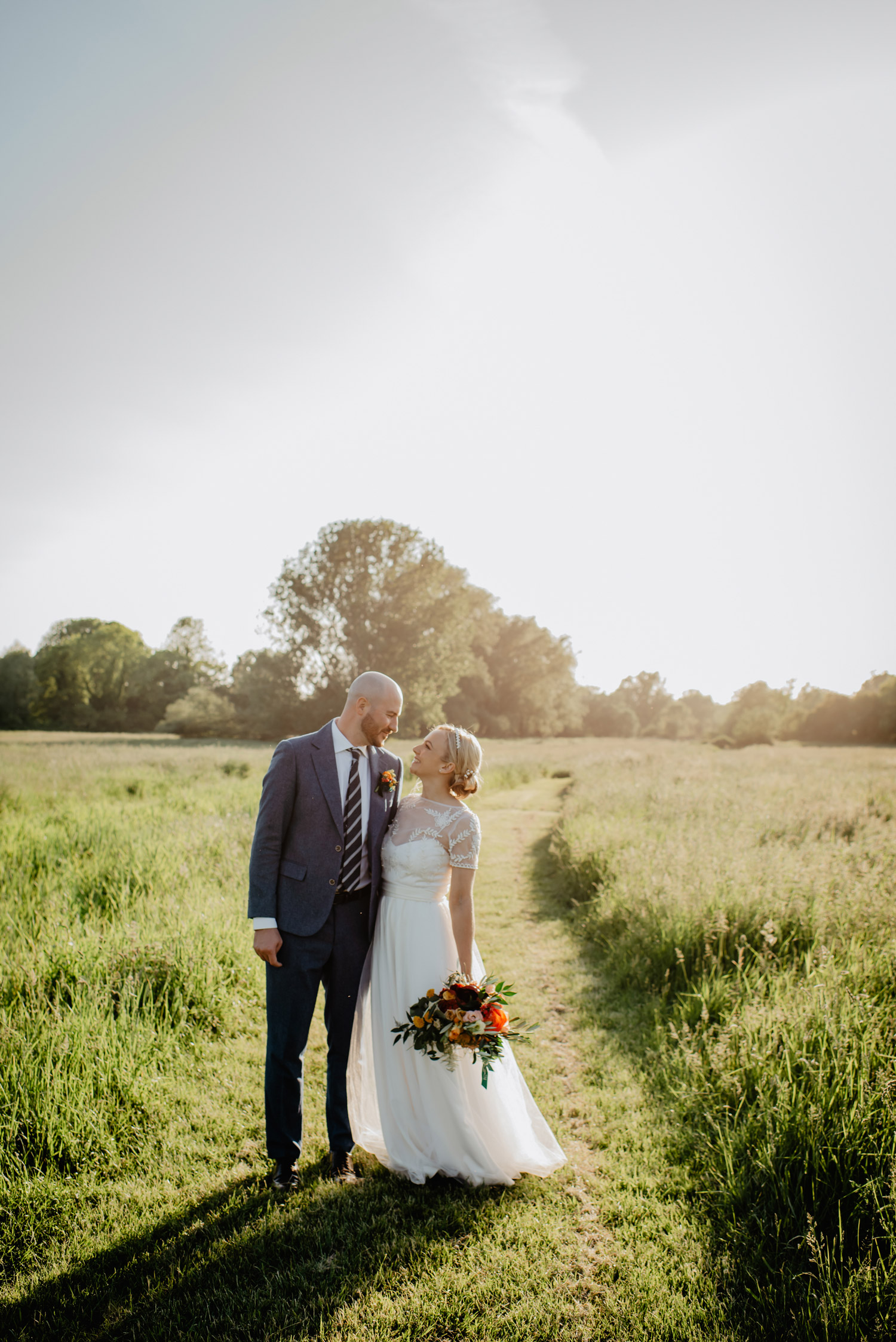 abbey hall eye suffolk wedding smiling bride walking down the aisle carrying a pink peony bouquet by anne schwarz photography