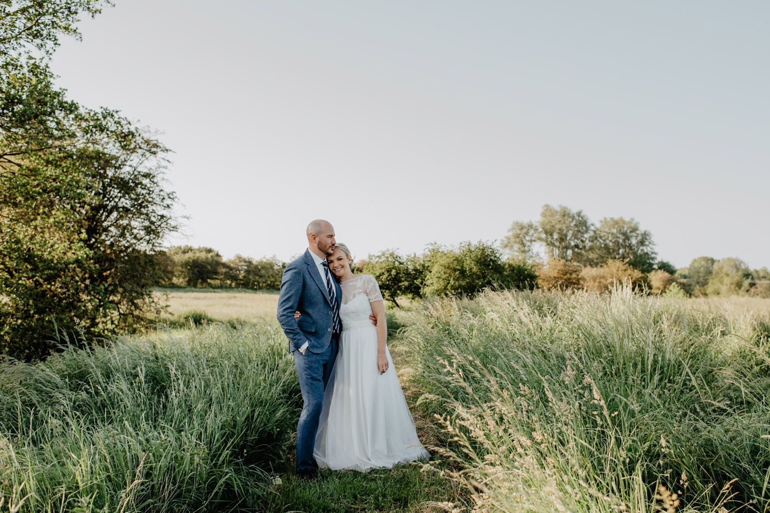 abbey hall eye suffolk wedding smiling bride walking down the aisle carrying a pink peony bouquet by anne schwarz photography