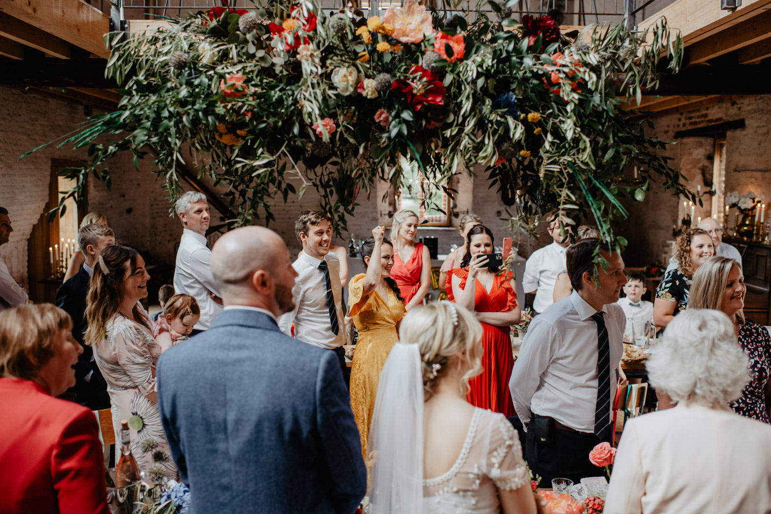 abbey hall eye suffolk wedding smiling bride walking down the aisle carrying a pink peony bouquet by anne schwarz photography