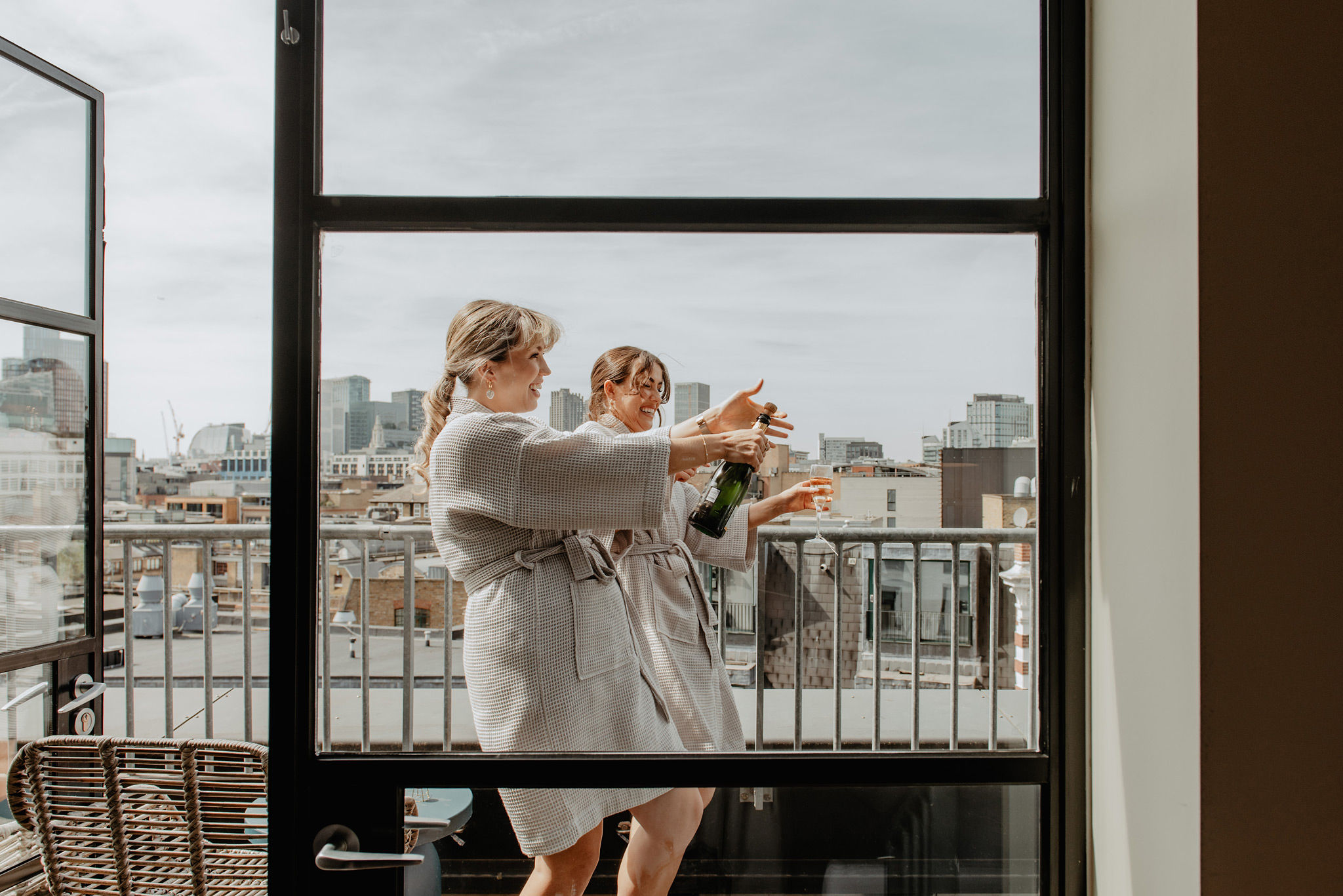 bridesmaids popping champagne on the balcony at one hundred shoreditch hotel 