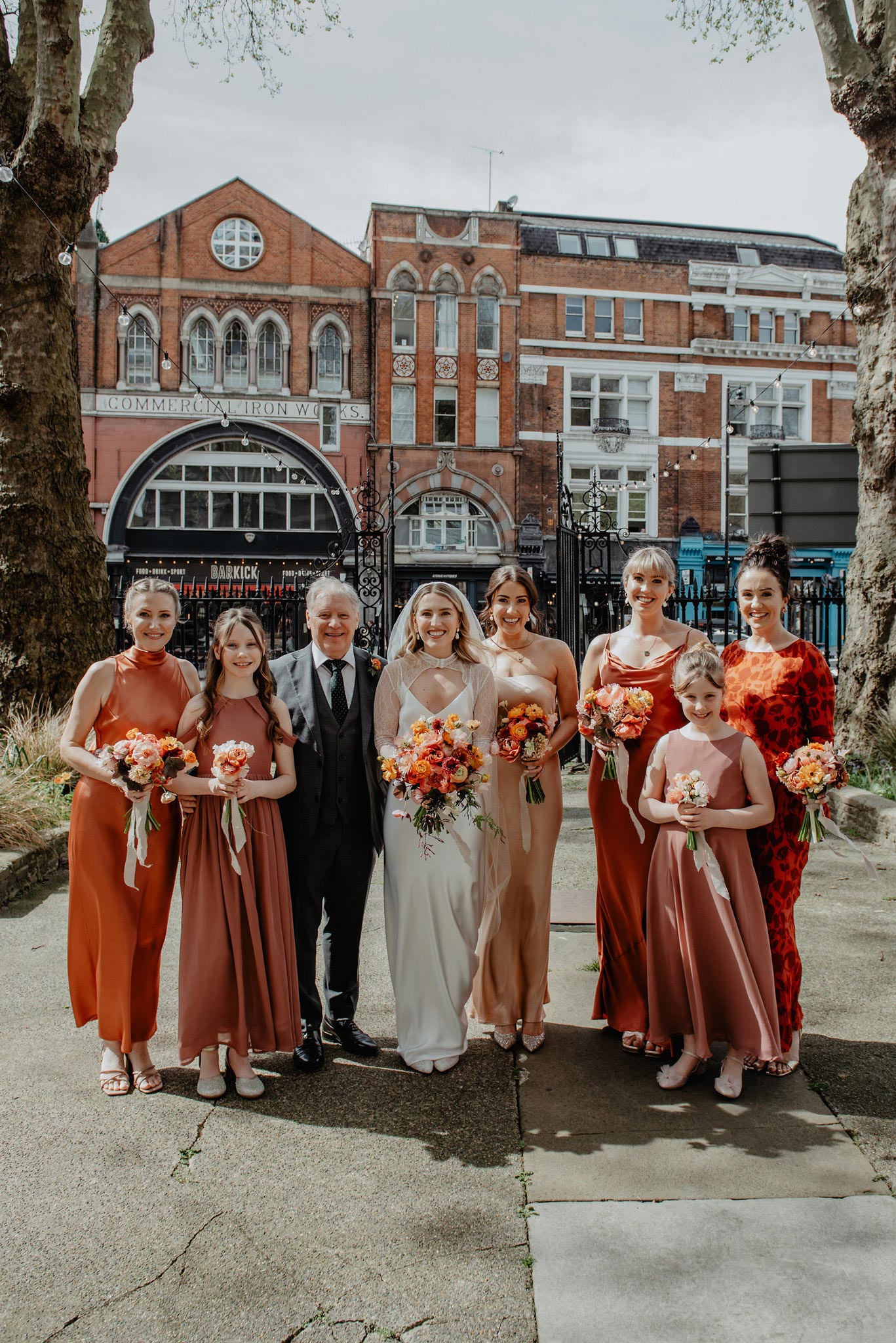 bride and bridesmaids in rust dresses outside shoreditch church before the wedding