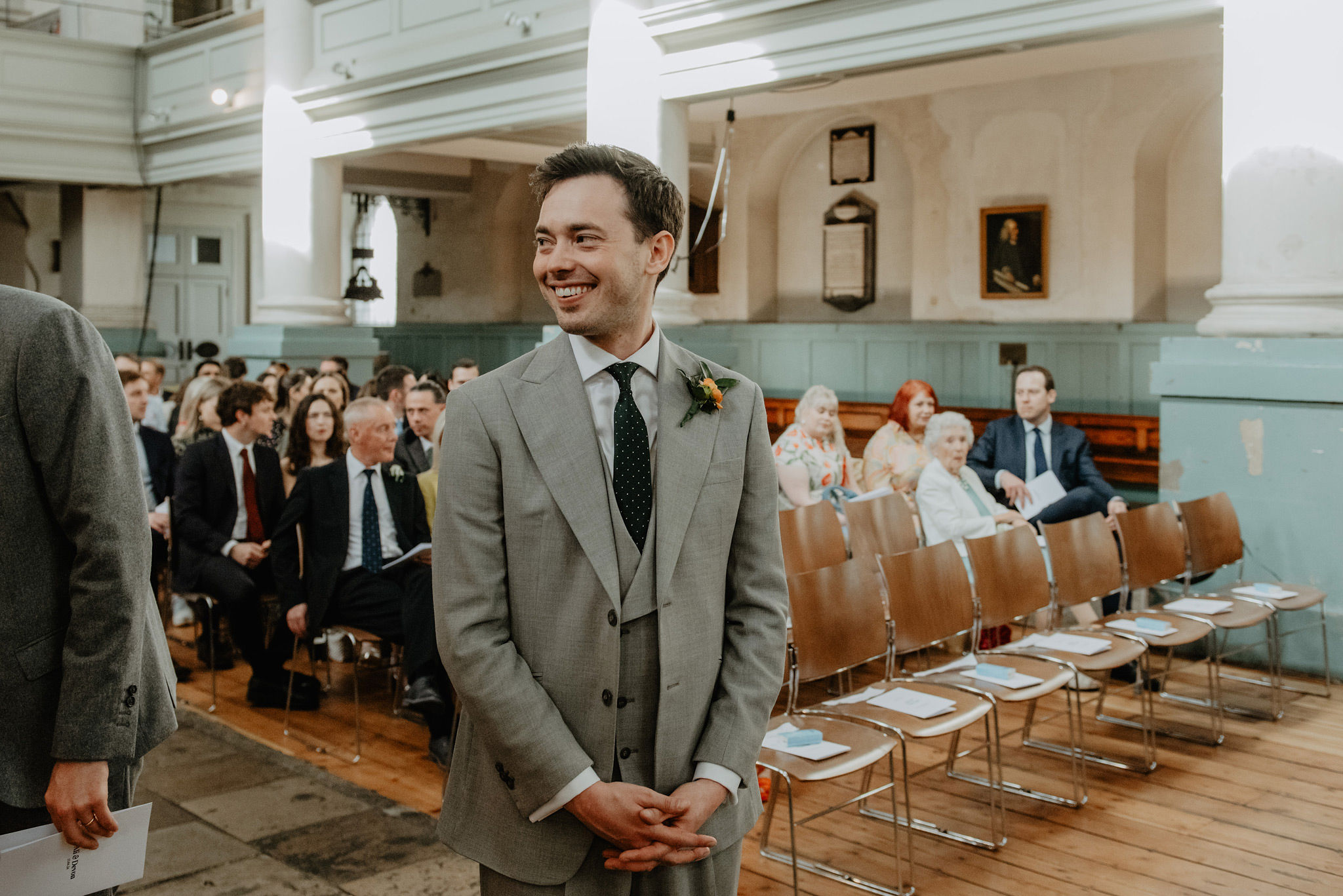 groom in grey suit waiting inside shoreditch church by anne schwarz wedding photography