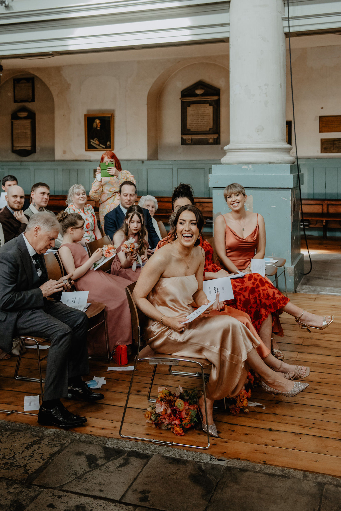 bridesmaids in blush satin laughing during wedding service at shoreditch church