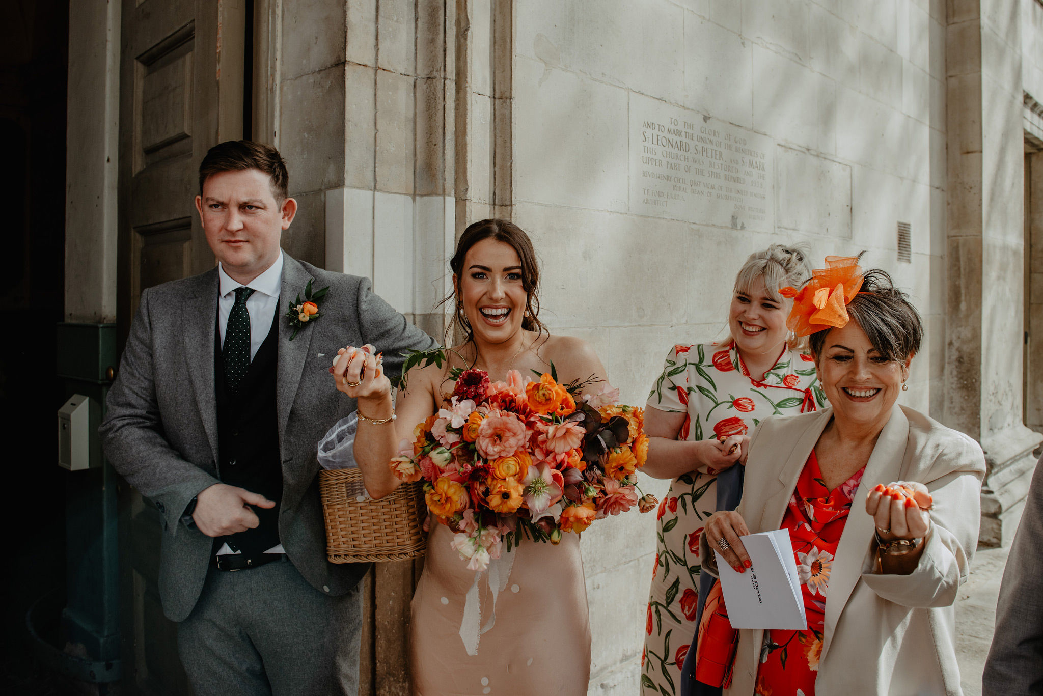 bridedsmaids with peach orange ranunculus bridal bouquet clutching confetti outside shoreditch church st leonards