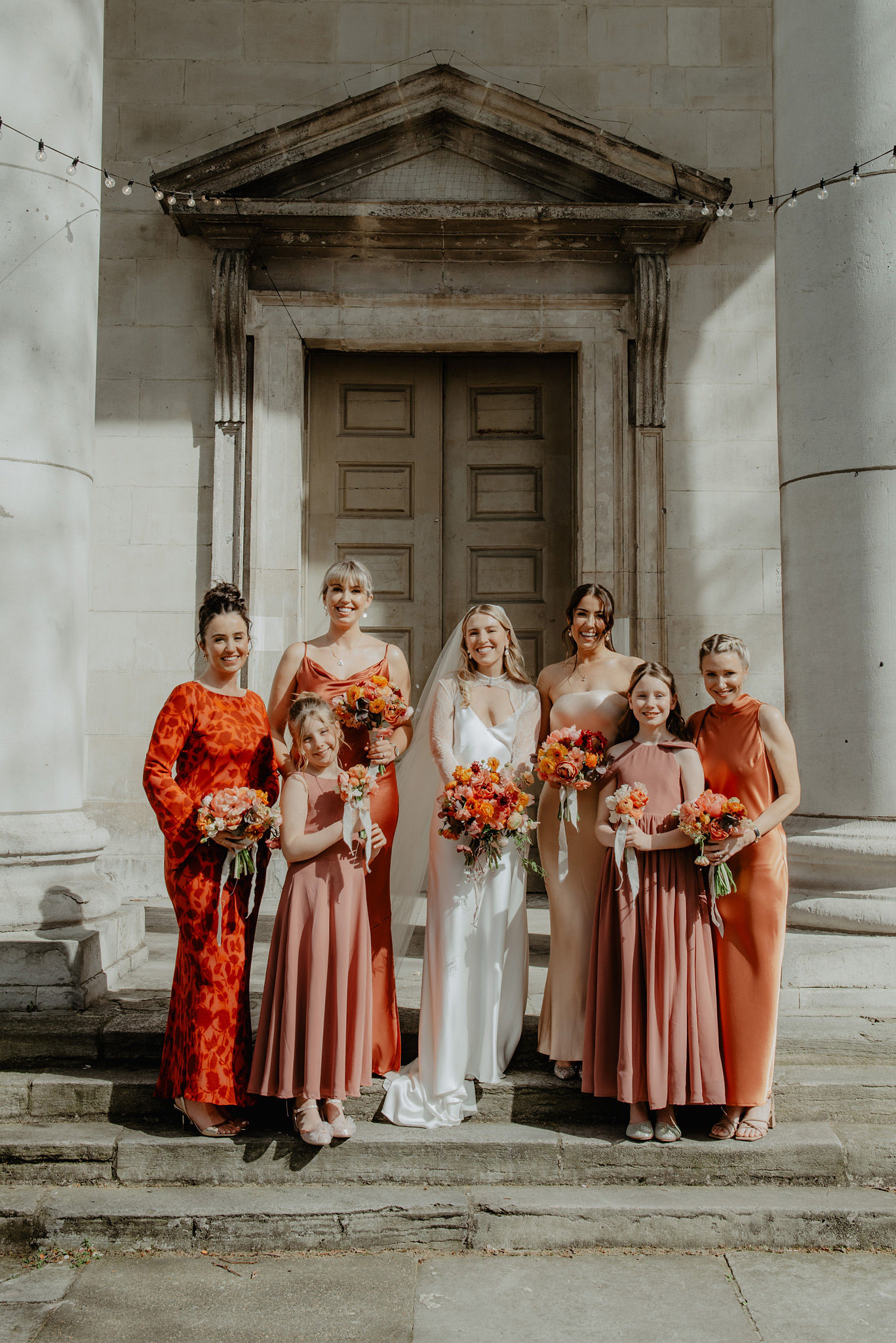 bridesmaids and bride in orange dresses outside church in shoreditch