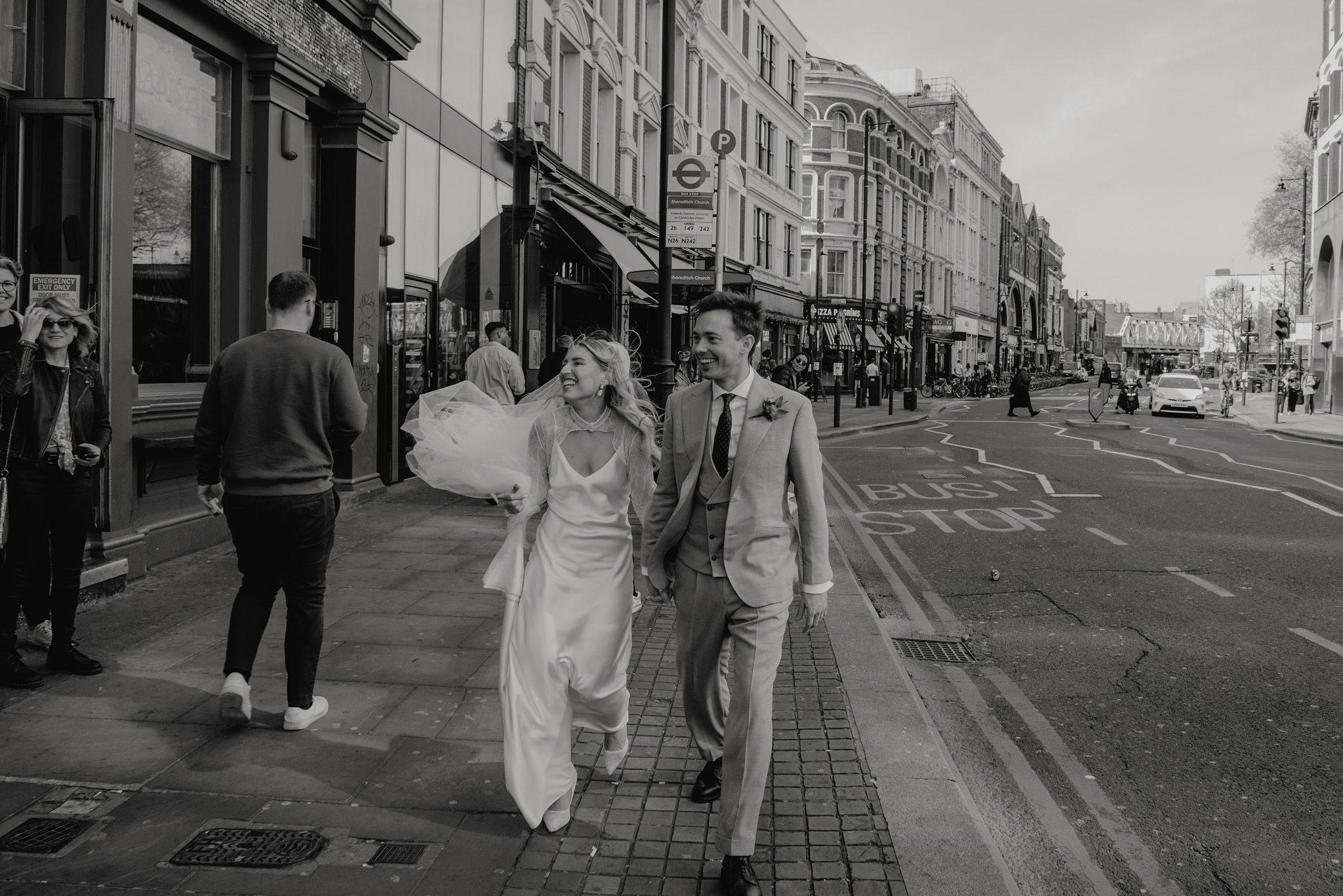 editoral photo of bride and groom walking on shoreditch high street after church wedding 