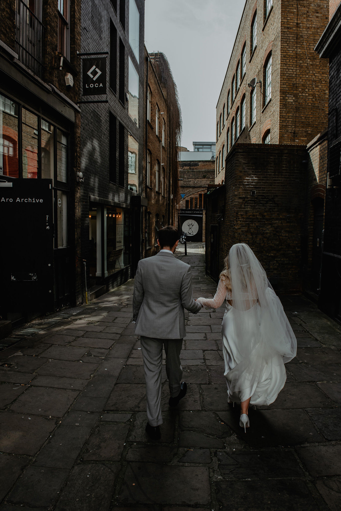 editorial style wedding photo of bride and groom walking from behind at shoreditch studios 