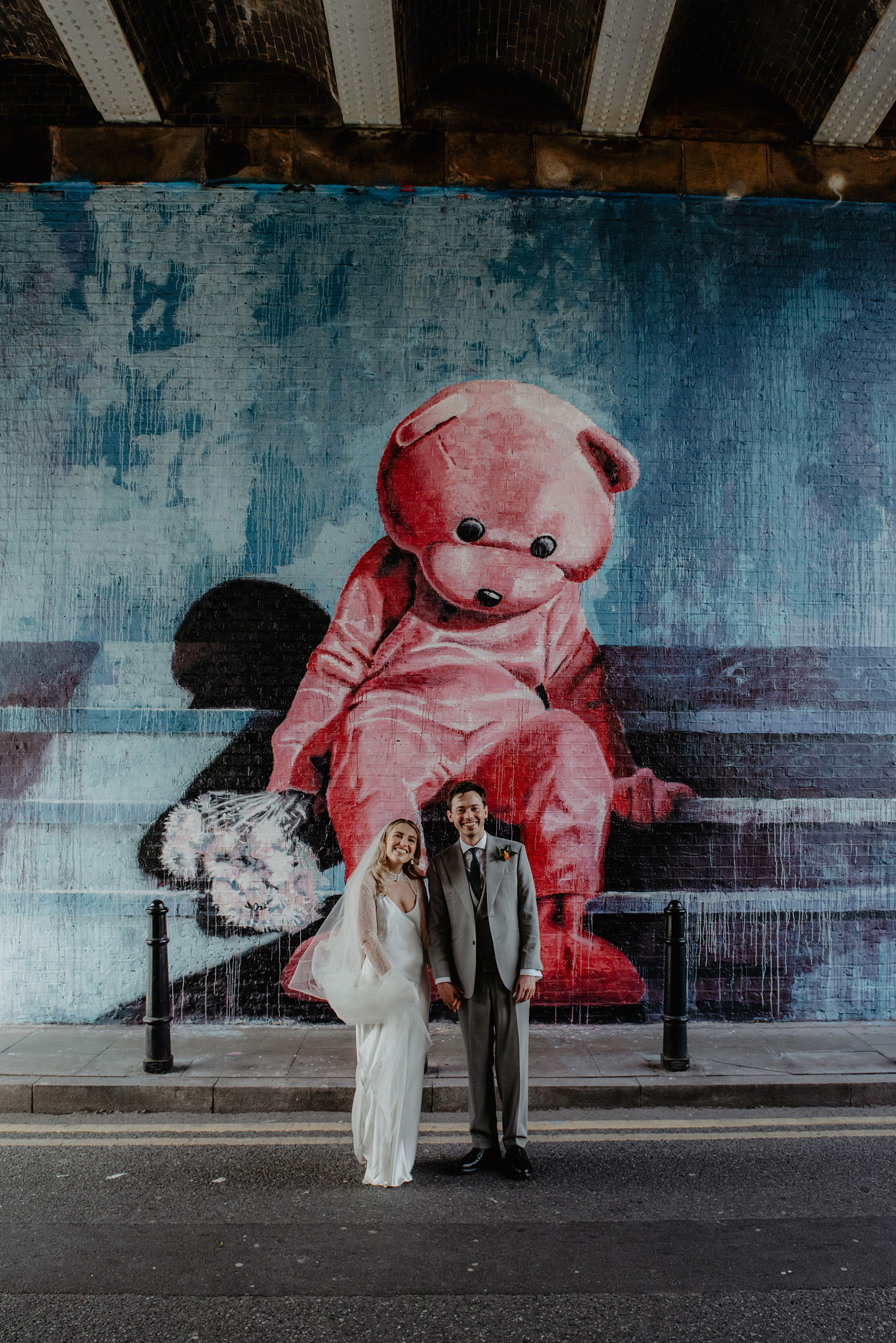 bride and groom in front of pink teddy mural at shoreditch studios wedding